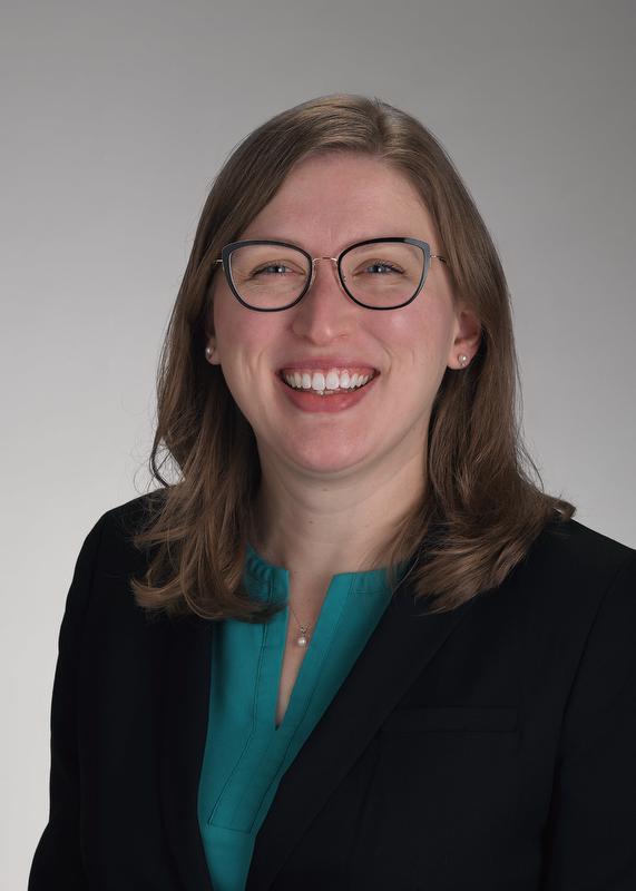 Photo of Jess Meyer smiling at camera in green shirt and black jacket